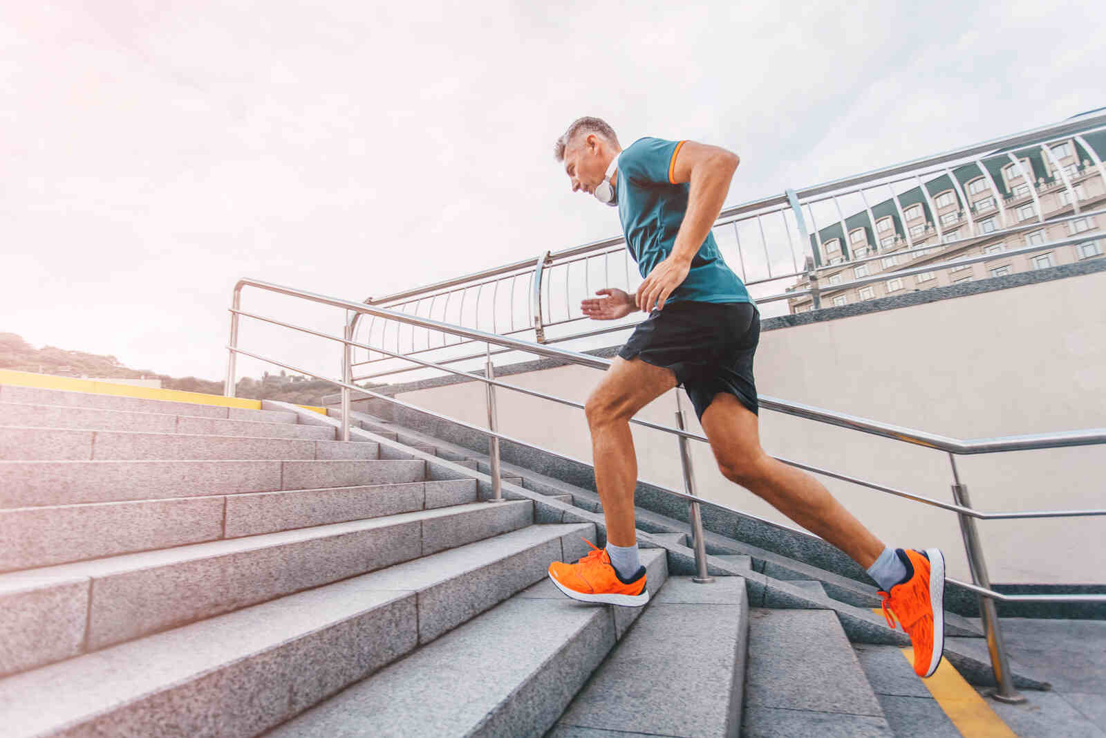 middle aged man runner running upstairs on city stairs 