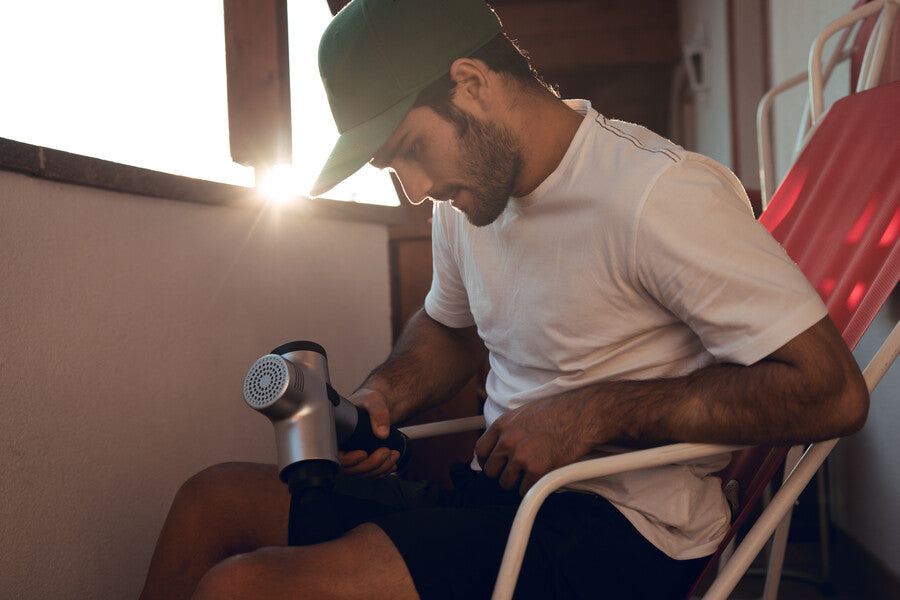 Man massaging with machine to massage gun at sunset